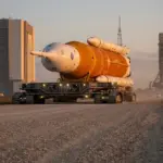 The Artemis II SLS rocket rolling back to the Vehicle Assembly Building at dusk.