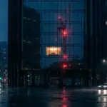Nighttime view of a modern fintech office building with red warning lights reflection