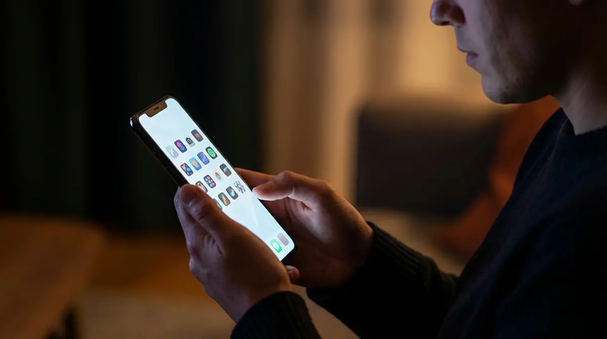 Smartphone user browsing alternative app icons in a dimly lit setting.