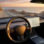 Tesla Model 3 interior view driving on a California highway during sunset.